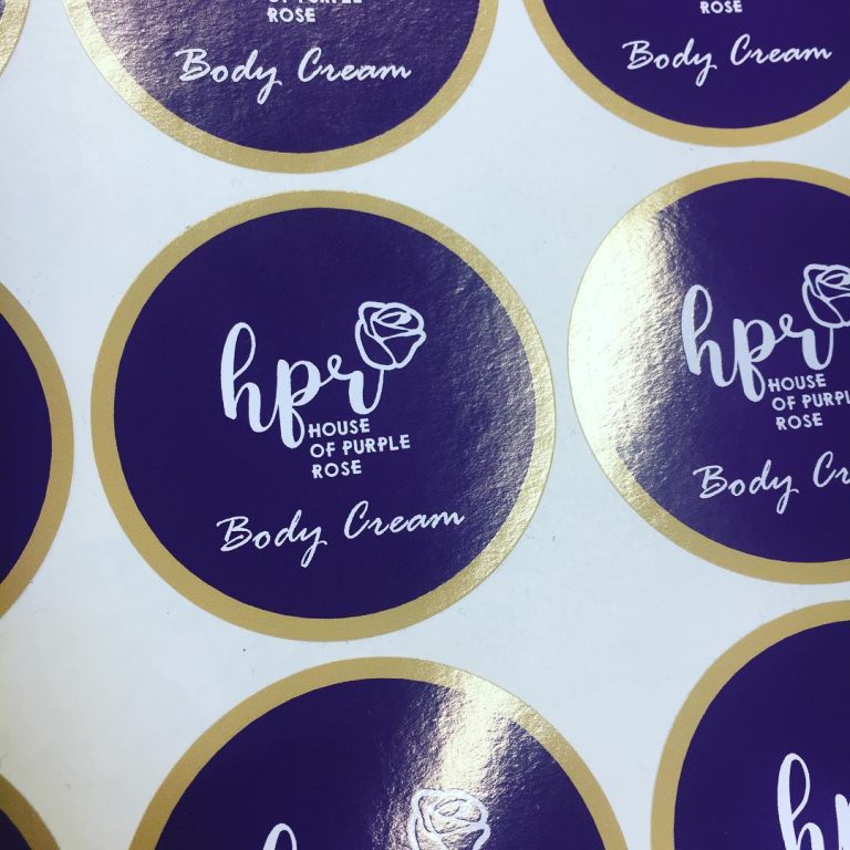 Custom glossy vinyl body cream labels in purple and gold branding – waterproof high-shine stickers
