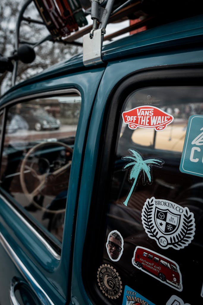 Close-up of a classic car showcasing a variety of colorful stickers on its window.